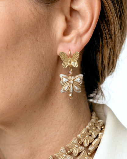 Modelo luciendo los Pendientes Papillon Blanc con mariposas de cristal blanco nácar y dorado
